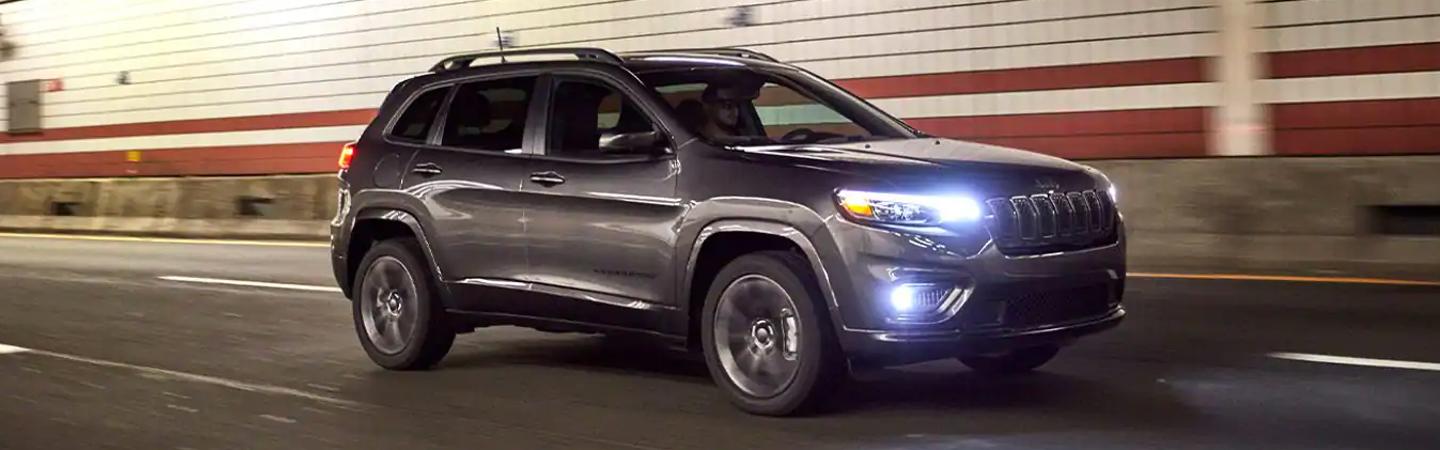 Side view of a grey Jeep Cherokee driving through a tunnel.