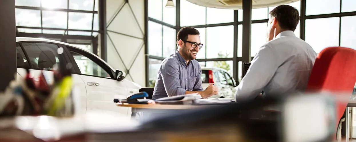 Car salesman and customer sitting at a table and smiling
