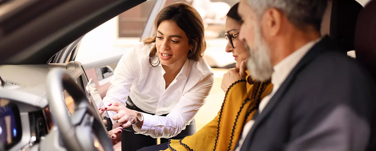 Car sales woman showing a couple a new vehicle