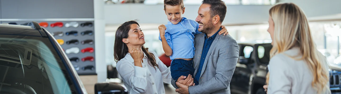 Happy family with sales person talking about there new car