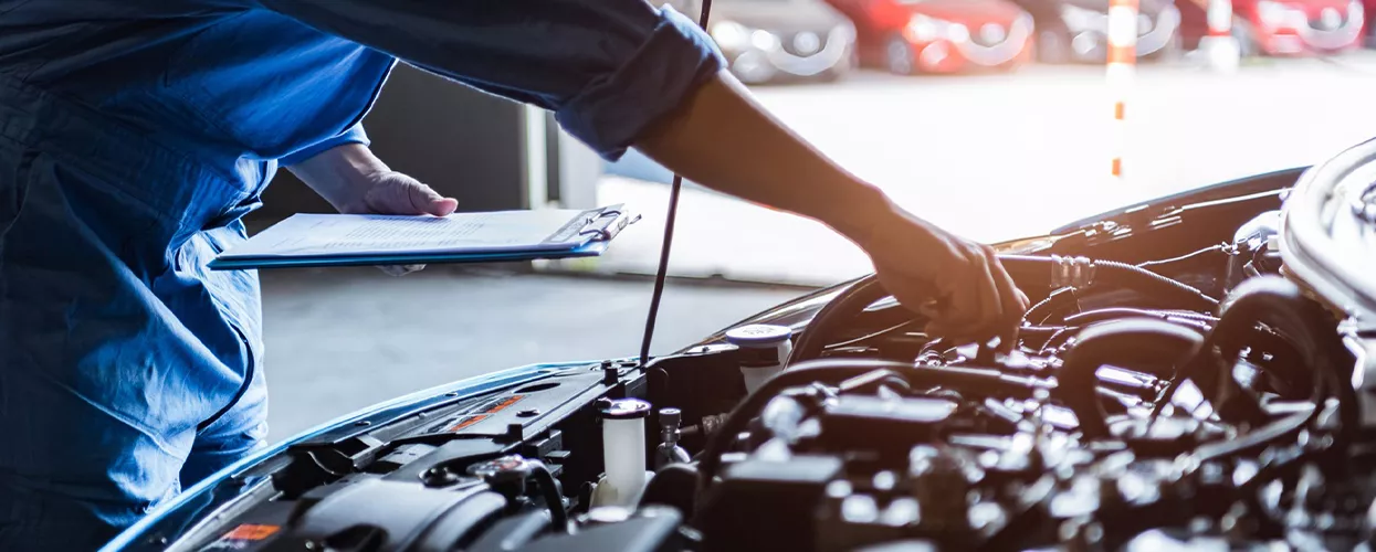 Service mechanic working on a car with the hood up