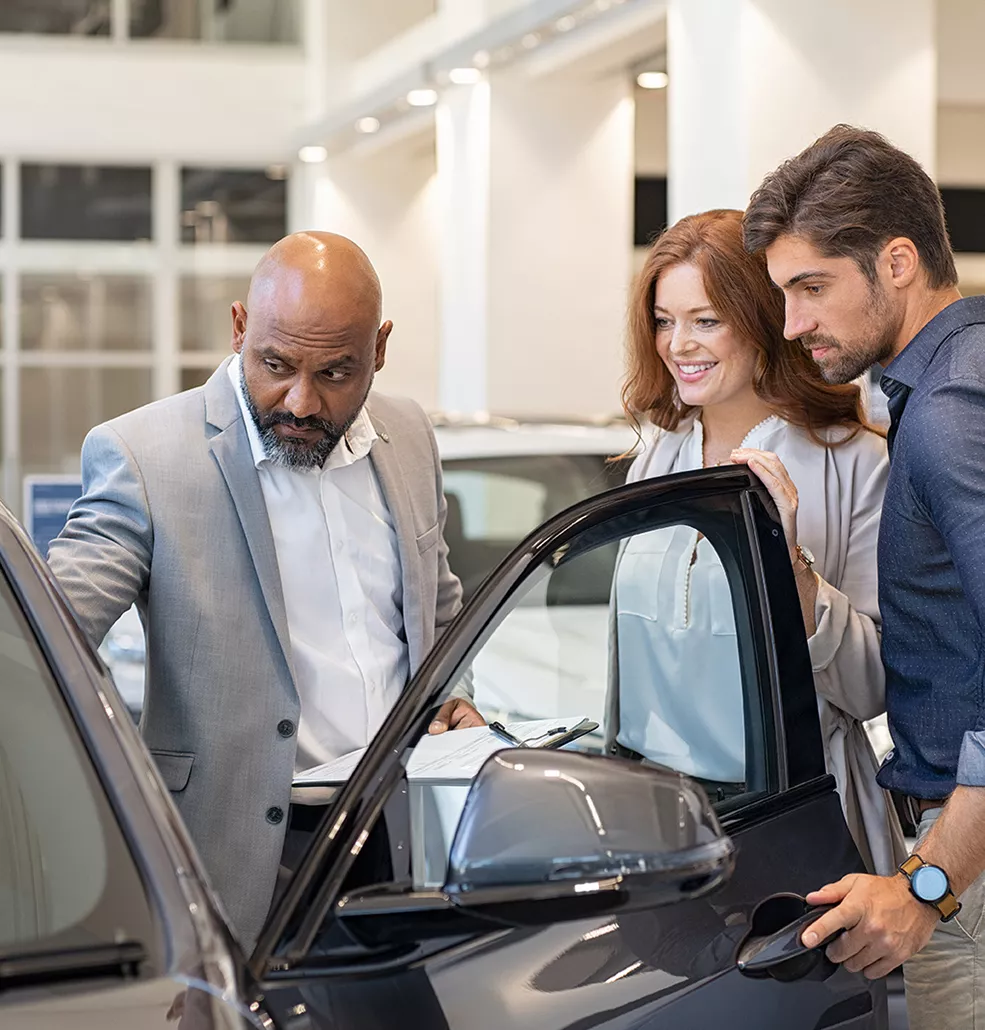 Car salesman showing a couple a new car