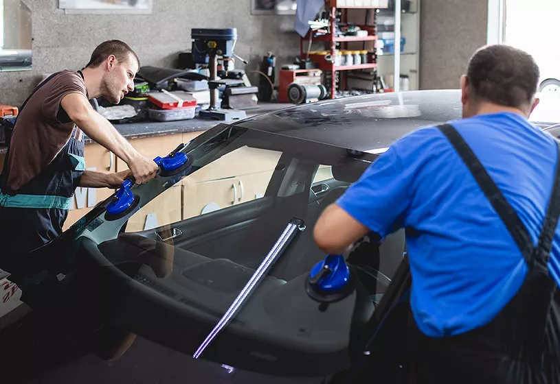 car mechanics working on windshield of car