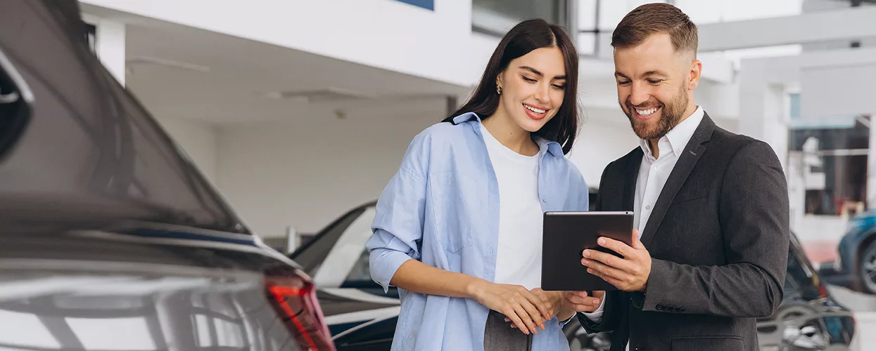 Car dealership sales consultant reviewing vehicle features and purchase options with a customer