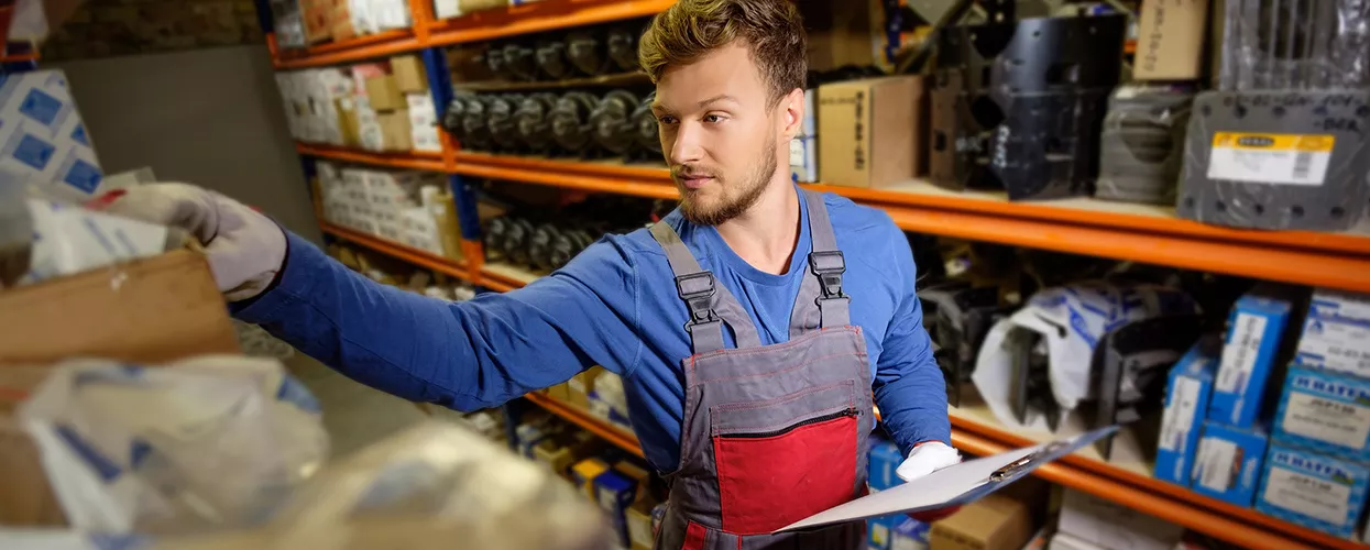 Service mechanic looking for parts and holding a clipboard