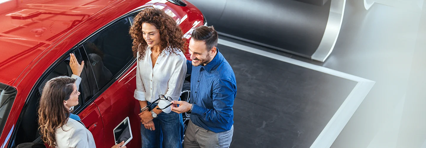 couple speaking with another person by a car after a test drive