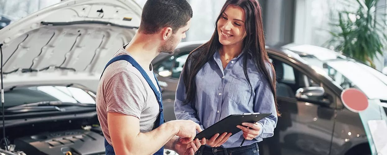 Automotive service advisor reviewing vehicle maintenance recommendations with a customer in a professional dealership service center