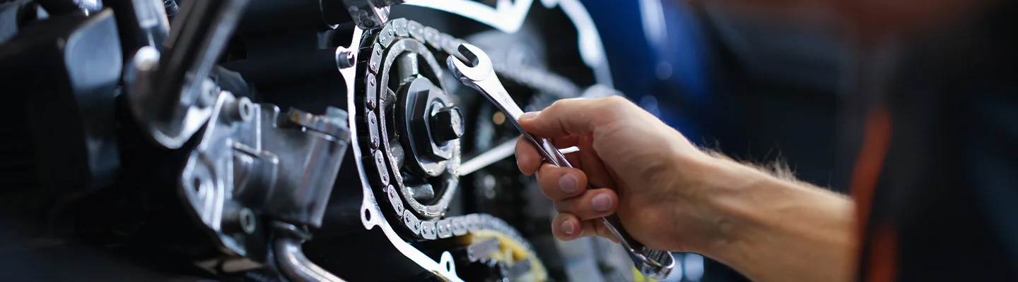 an auto mechanic holding a tool working inside engine