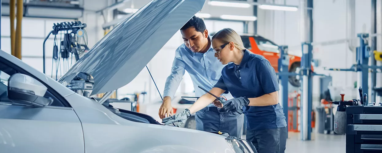 Service mechanics working under the hood of a car