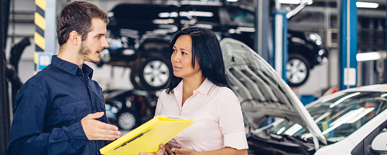 Service mechanic talking to a car owner and holding a clipboard