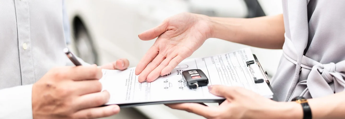 two people's hands one with clipboard with car keys on it