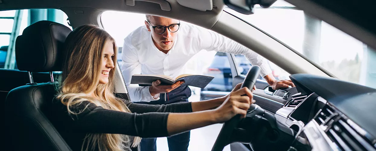 Car salesman showing a woman the interior of a new vehicle