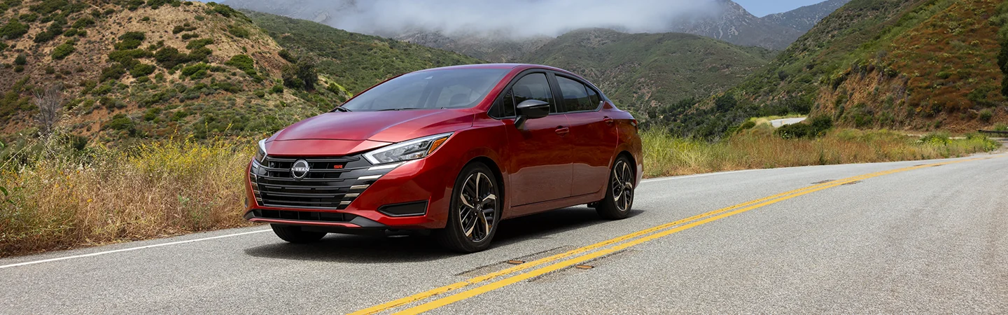 front view of a red 2025 Nissan Versa SV on a mountian road