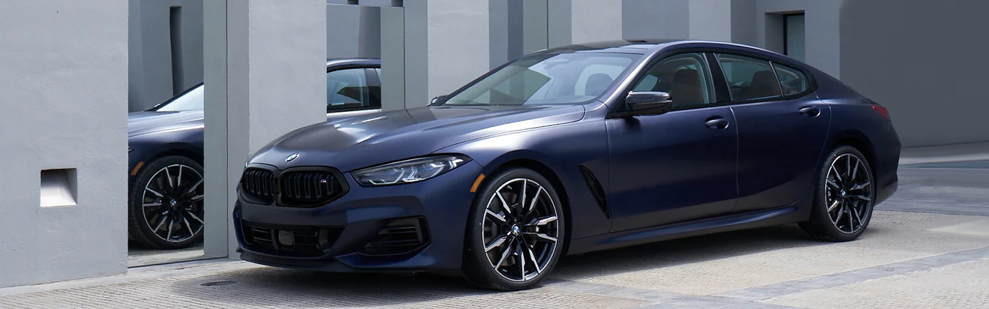 Side view of a parked 2025 BMW 8 Series in fornt of a house