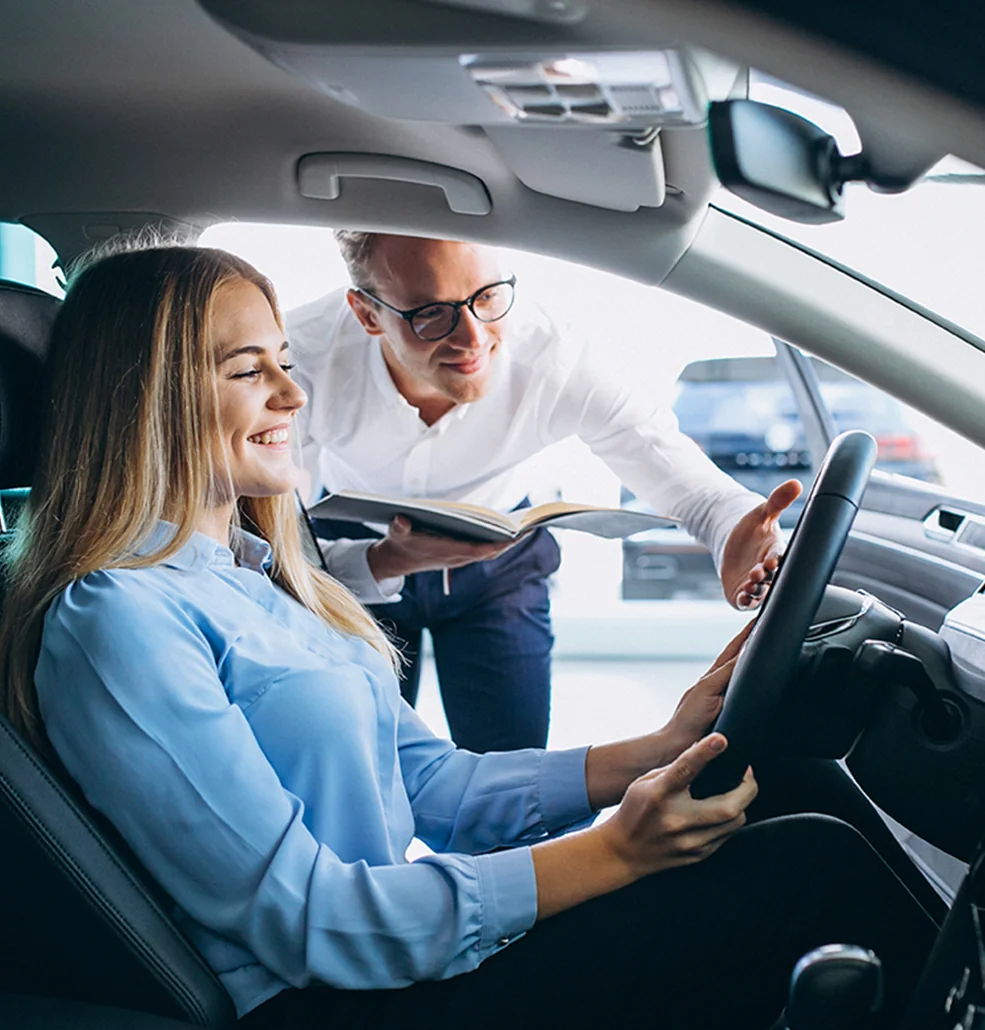 Inside a car, a man and woman share a moment, reading a book together.
