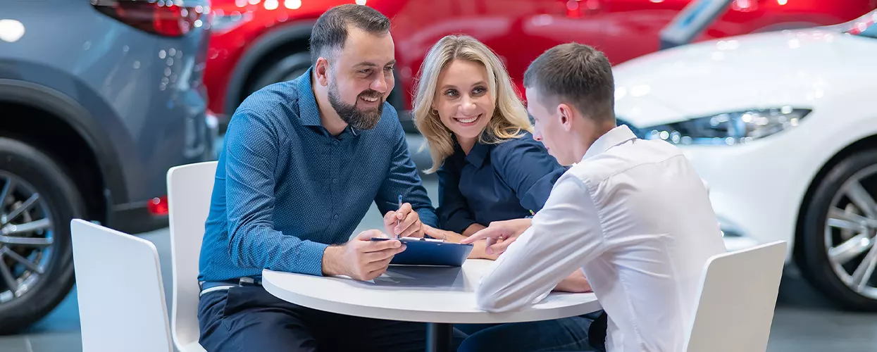 husband and wife signing documents with salesman at a table
