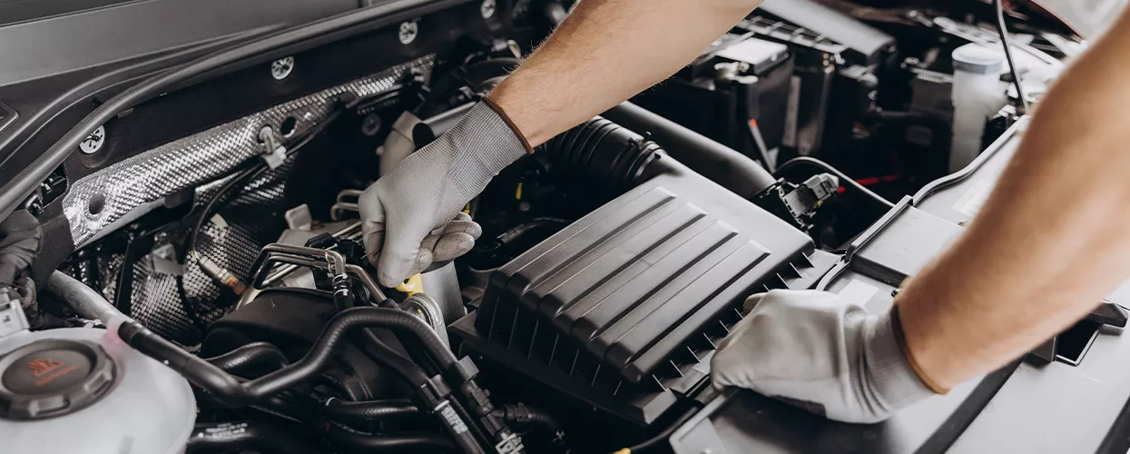 Service mechanic working under a hood of a car