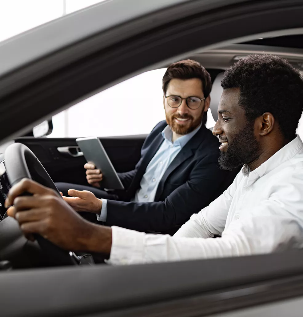 Car salesman and customer sitting in a new vehicle