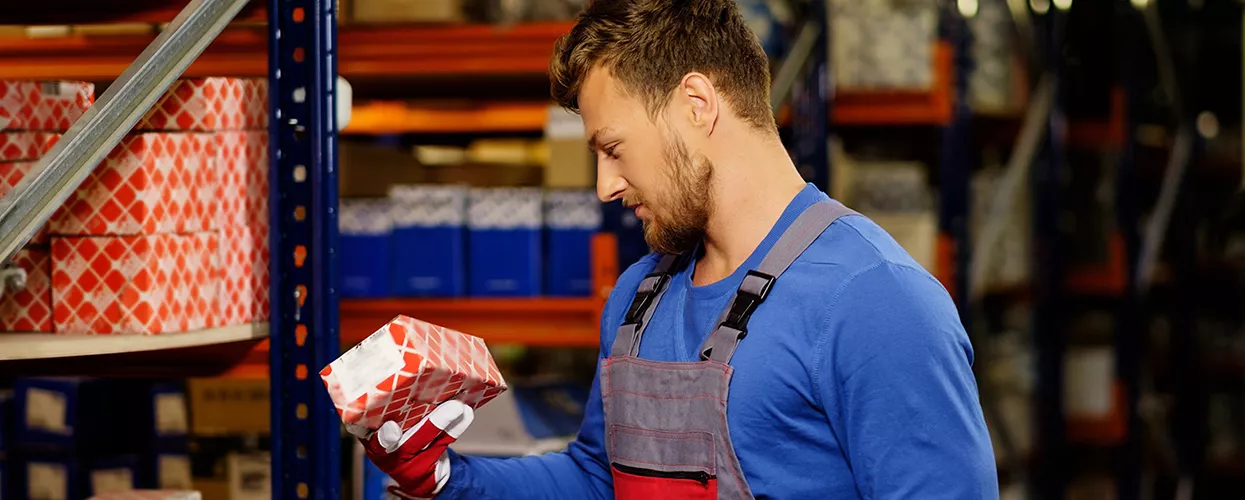 Blog Post in Automotive parts technician checking inventory in an auto parts warehouse while holding a replacement vehicle component box