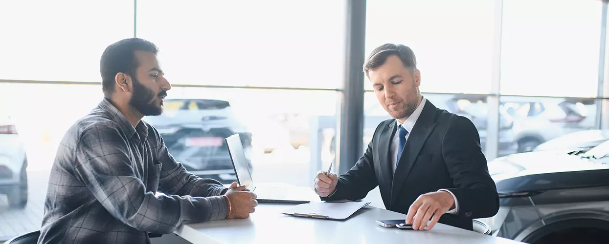 Dealership finance specialist discussing vehicle financing and purchase options with a customer in a modern showroom