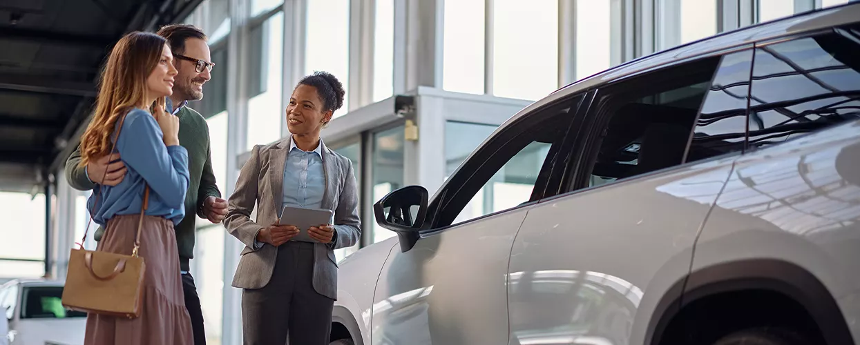 Car sales consultant assisting customers with vehicle selection inside a modern dealership showroom