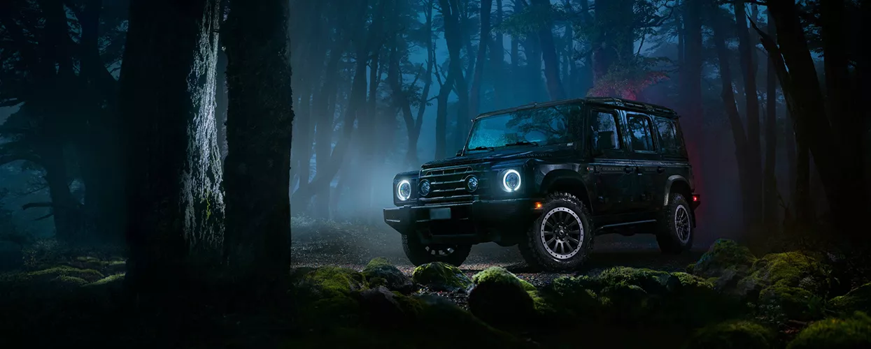 INEOS vehicle driving in a forest at night