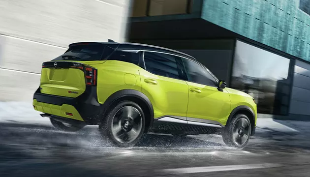 Back side view of a green Nissan SUV driving thought water in a city