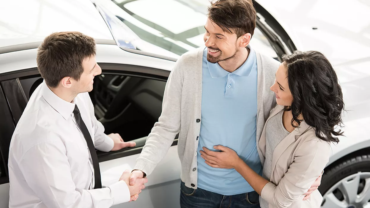 Car salesman showing a couple a new car
