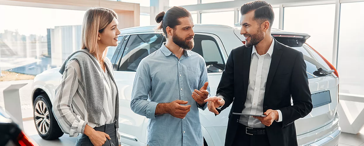Car salesman talking to a couple in a car dealership