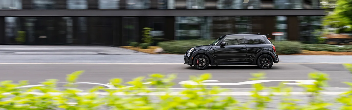 black 2025 MINI Cooper 2 Door driving by some flowers