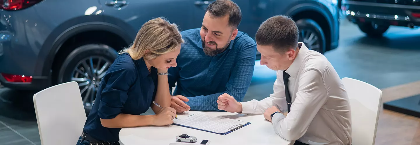 Three people sitting at a table looking over a contract