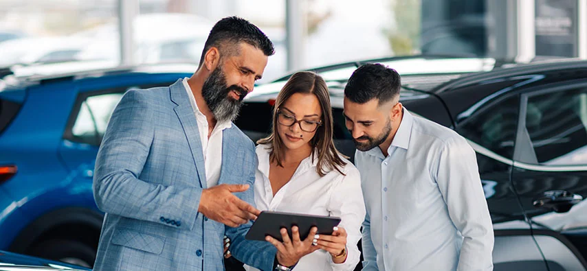 a couple speaking with salesperson in dealership