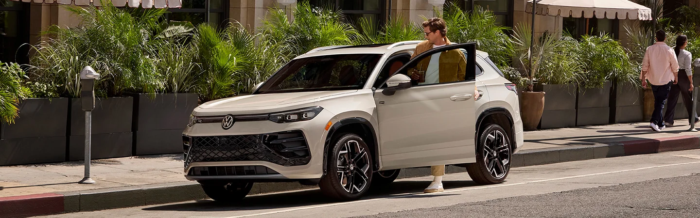 A person getting into a parked 2025 Volkswagen Tiguan on a city street
