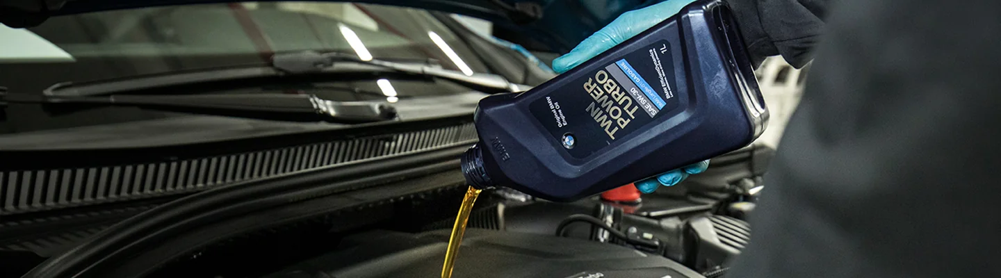 car mechanic pouring oil into engine