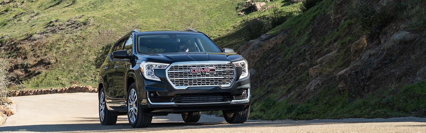 2022 GMC Terrain front view driving up small hill cut into mountain