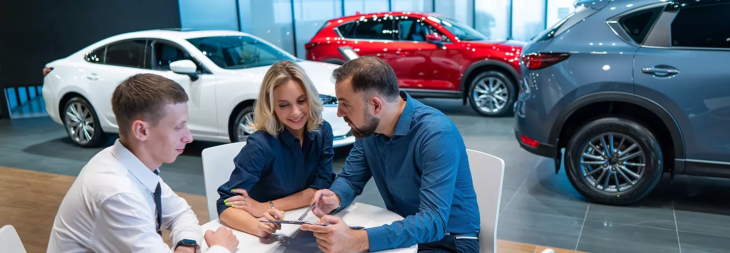 Car salesman talking with people at a car dealership