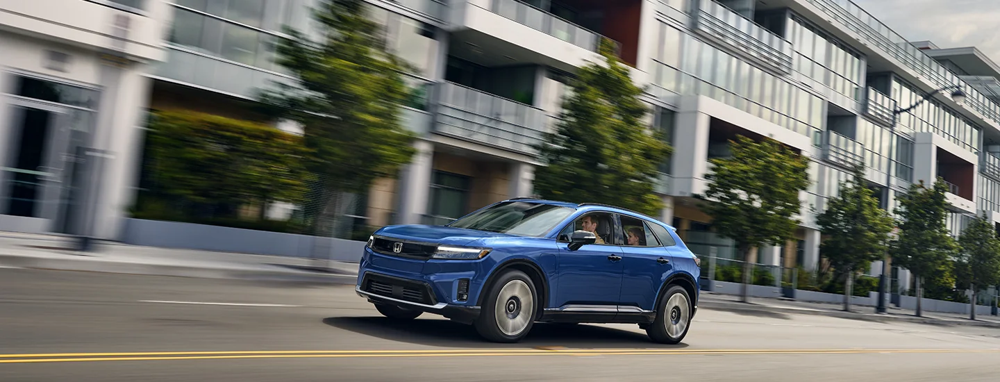 blue 2025 Honda Prologue in motion driving in the city