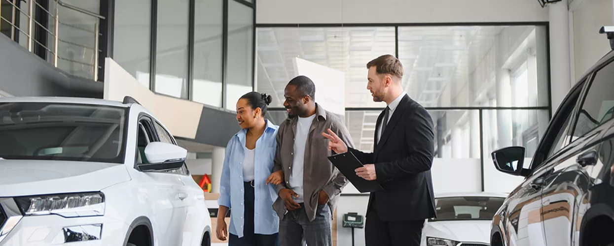 Car salesman showing a couple a new vehicle at a car dealership