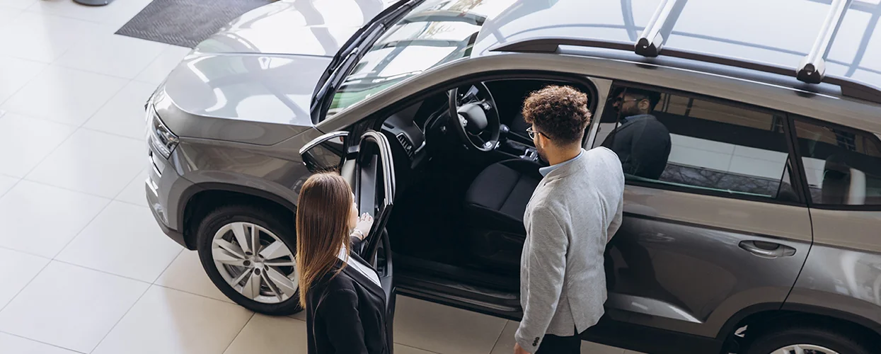 Two people looking over the inside of a tan Volkswagen SUV