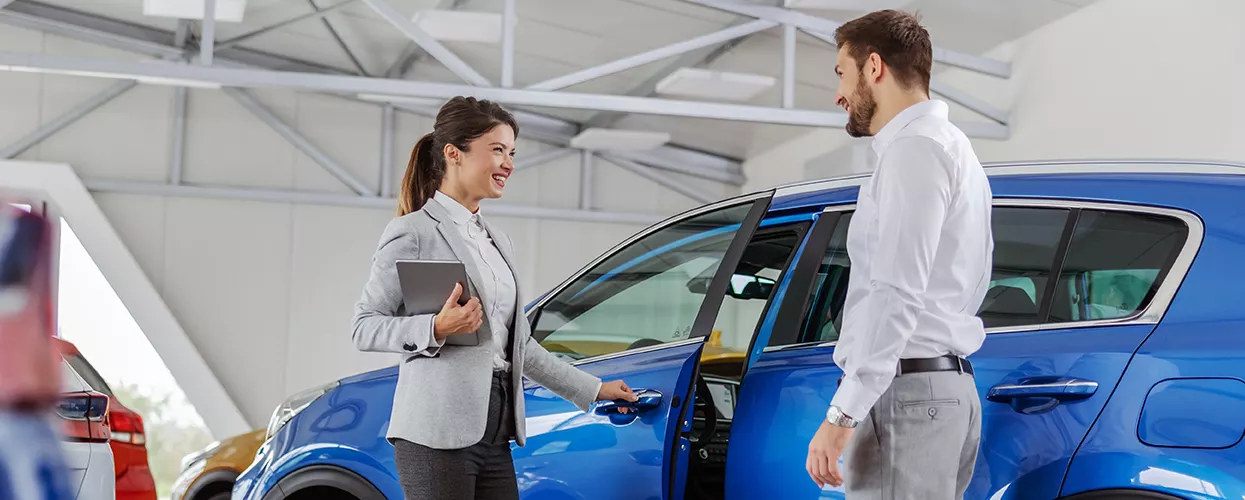 Salesperson showing a customer a row of used vehicles on a dealership lot