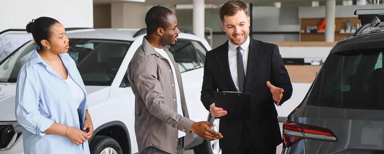 Car salesman showing a couple a new vehicle at a car dealership