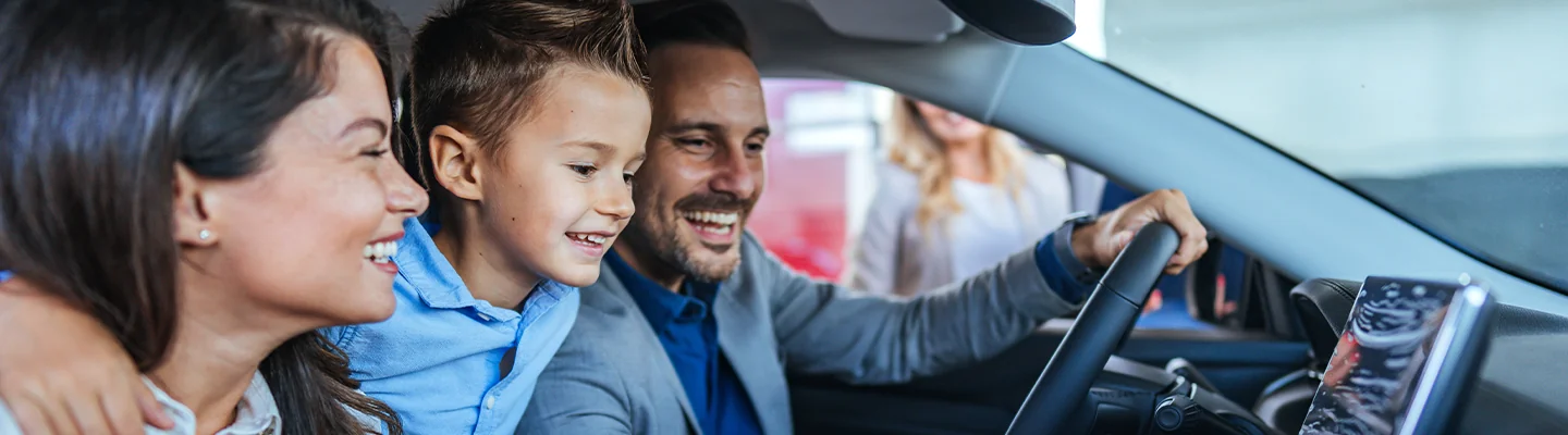 family of three looking at interior of car smiling