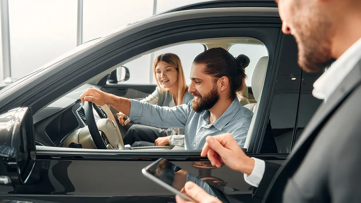 car salesperson showing lease details to customer sitting in car
