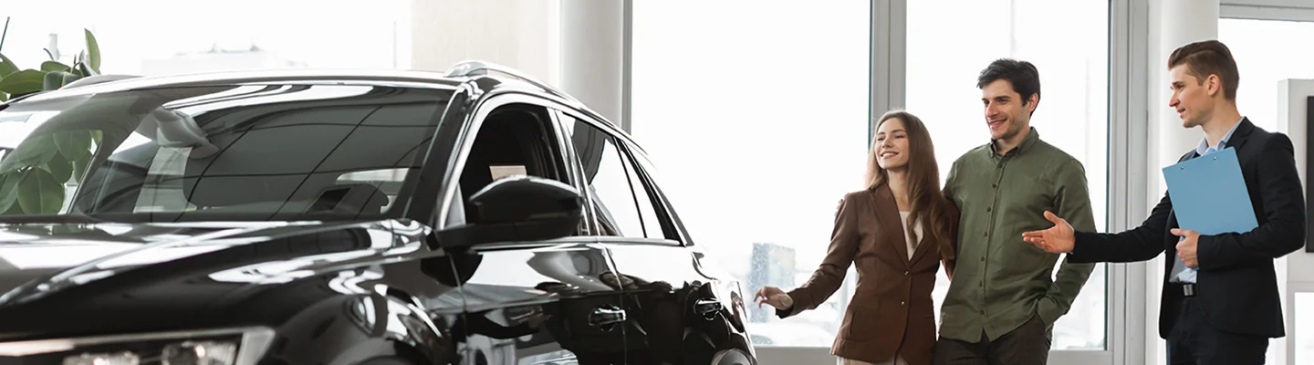 couple looking over a used car at dealership with salesperson