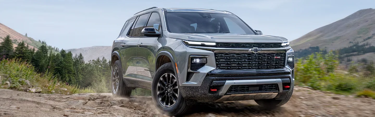 Front view of a gray 2024 Chevrolet Traverse driving in dirt