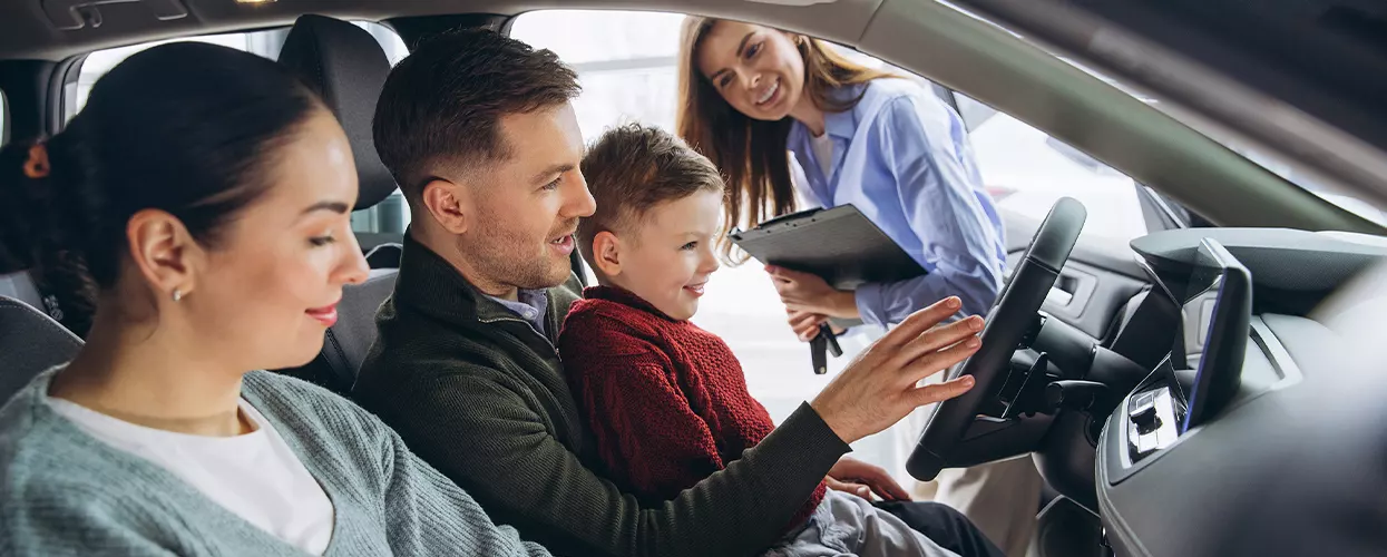 Family sitting in a vehicle at a car dealership