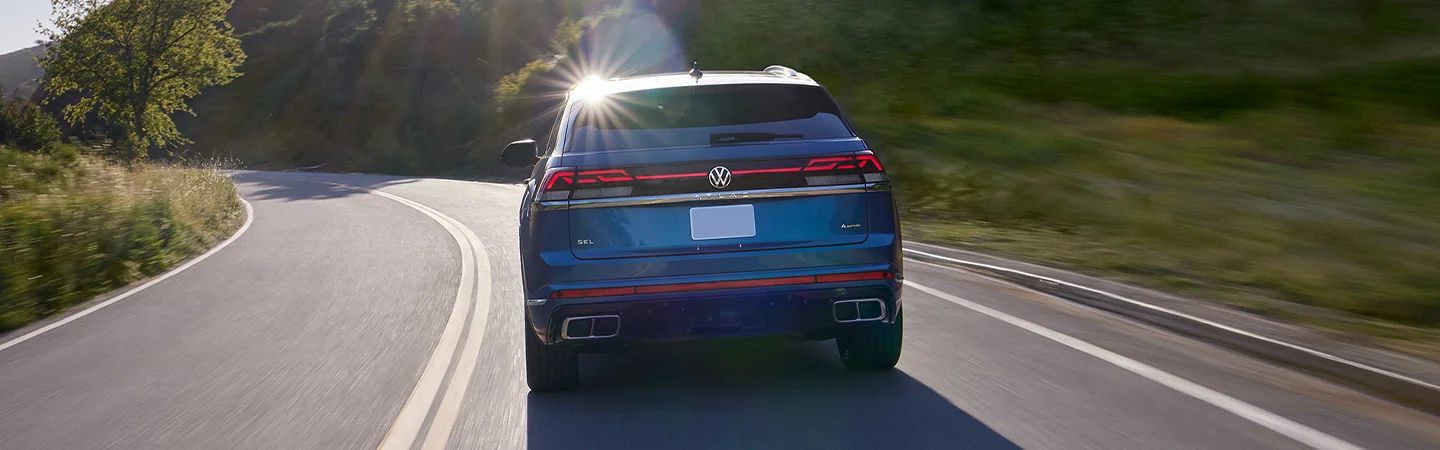 Rear view of the 2025 Volkswagen Atlas driving down a country road