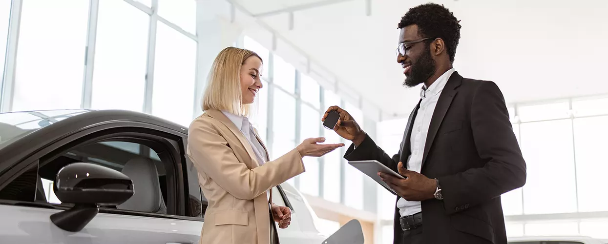 Car salesman handing over a set of new car keys to a customer