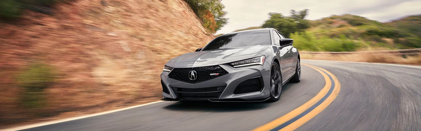 Front view of a gray 2025 Acura TLX driving on a road
