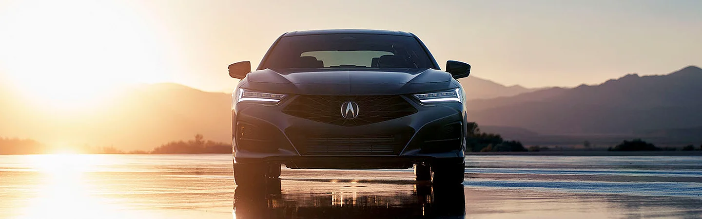 Front view of a parked 2025 Acura TLX with a sun in the background